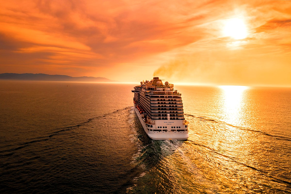 Ocean cruise ship sailing into a golden sunset