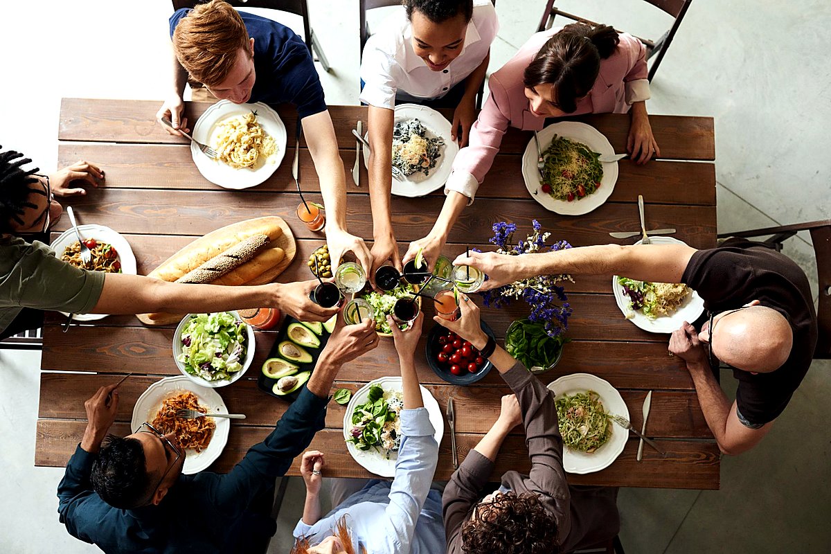 Overhead view of colleagues toasting glasses over a shared dinner table