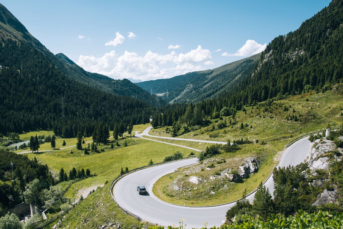 Winding road through a green alpine valley on a scenic guided tour route